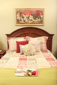 Beautiful bed, plush pillows, with a rose to complement the soothing decor